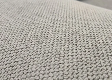 Minimalistinio dizaino pillkos spalvos sofa-lova su plačia miegamąja dalimi ir dėže patalynei.
