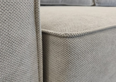 Minimalistinio dizaino pillkos spalvos sofa-lova su plačia miegamąja dalimi ir dėže patalynei.